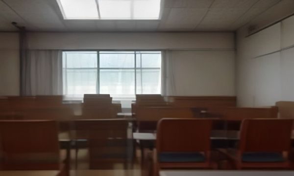 日本中学教室内，阳光斜射在空旷的座位上，气氛压抑，对应《告白》中校园复仇伦理的核心场景